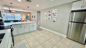 A modern kitchen with white cabinetry, a stainless steel refrigerator, and a central island.