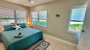 A bedroom with a bed, a starfish decoration, a window with blinds, and a door.