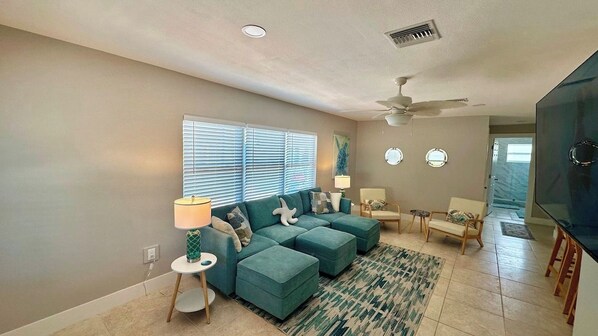 A living room with a sectional sofa, a television, and a ceiling fan.