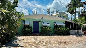 A single-story building with a blue door, awnings, and a paved driveway. - Turtle Nest Beach House (Fort Myers Beach)