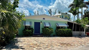 A single-story building with a blue door, two awnings, and a paved driveway. - Turtle Nest Beach Studio - Quick Walk to Beach (Fort Myers Beach)