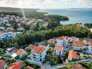 An aerial view of a coastal residential area with houses, a beach, and a clear sky. - Apartments Sweet Memories - (Supetar)