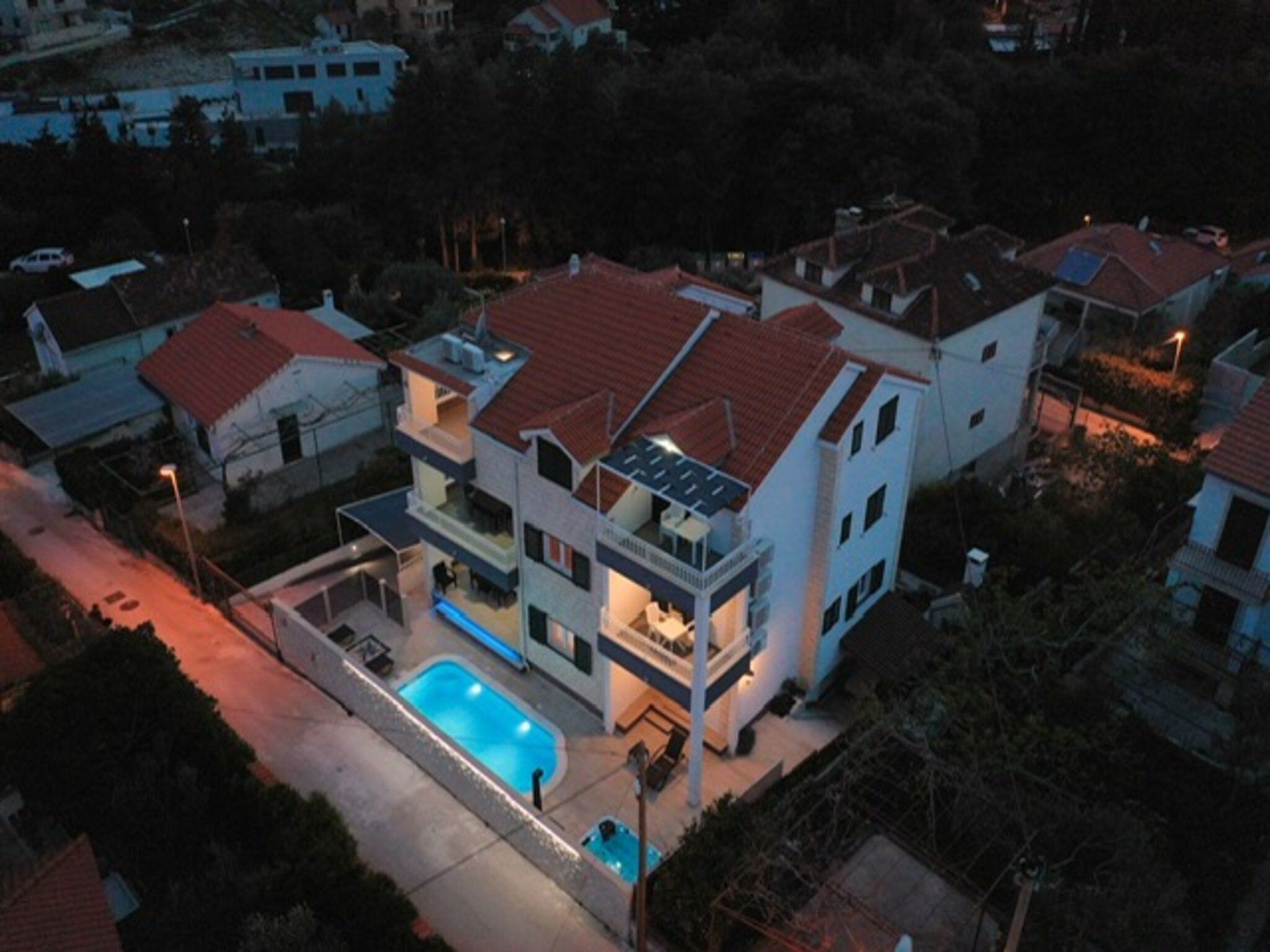 Ein modernes, zweistöckiges Haus mit Swimmingpool, umgeben von anderen Wohngebäuden.