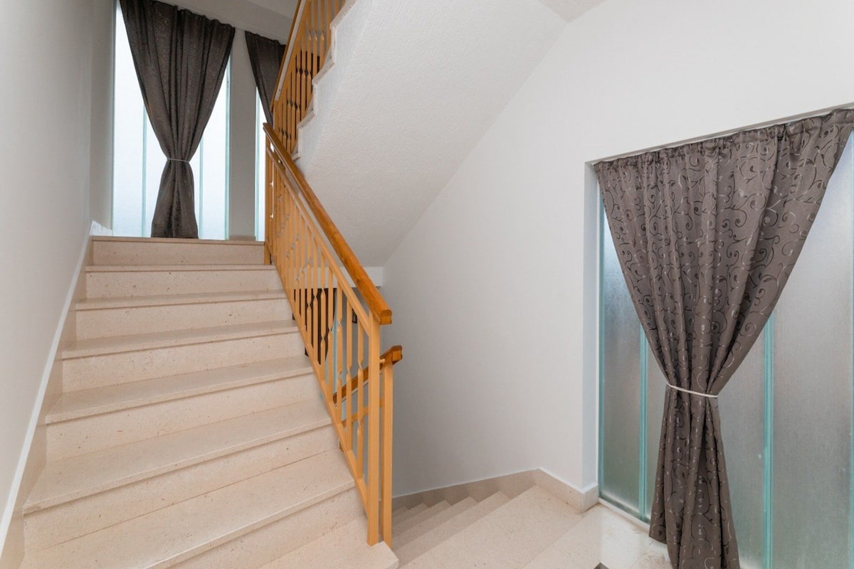 A staircase with wooden railings and beige steps leading to an upper floor.