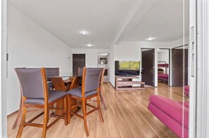 A modern living room with a dining area, a TV, and a pink sofa. - Spacious Apt Near Centro Historico (Mexico City)