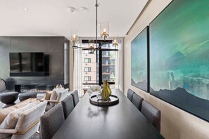 A modern living room with a fireplace, a dining table, and a large painting.