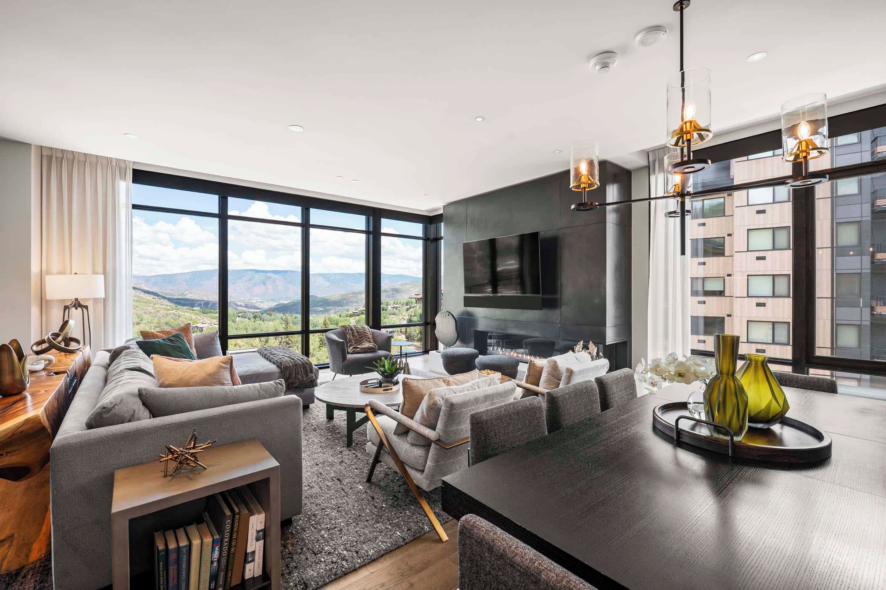 A modern living room with a large window, a fireplace, and a dining area.
