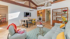 A modern living room with a sofa, a dining table, and chairs. There is a kitchen area with a stove and cabinets. - Stylish Apartment with Spacious Terrace in Florence's Historic Center (Firenze)