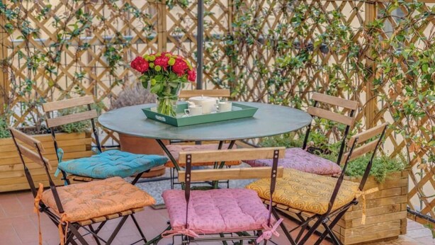 A round table with a tray of white cups and a vase of red flowers. - Stylish Apartment with Spacious Terrace in Florence's Historic Center (Firenze)