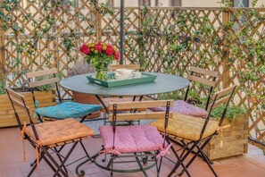 A round table with a tray of white cups and a vase of red flowers. - Stylish Apartment with Spacious Terrace in Florence's Historic Center (Firenze)