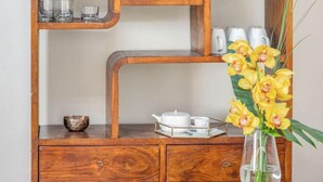 A wooden cabinet with multiple shelves, a vase with yellow flowers, and a teapot on the lower shelf. - Stylish Apartment with Spacious Terrace in Florence's Historic Center (Firenze)