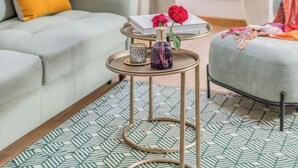 A living room with a light grey sofa, a small round table with a tray holding books and flowers, and a patterned rug. - Stylish Apartment with Spacious Terrace in Florence's Historic Center (Firenze)