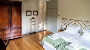A bedroom with a wooden wardrobe, a bed with white bedding, a bedside table with a lamp, and a wooden headboard. - Quinta dos Murças (Peso da Régua)