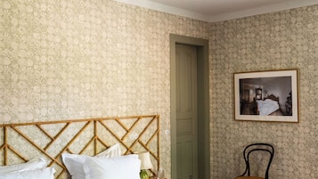 A bedroom with a bed, a chair, a picture on the wall, and a ceiling fan.