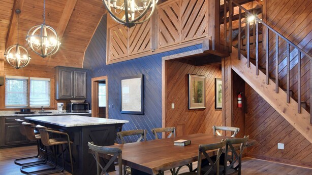 A spacious kitchen with a large island, wooden ceiling beams, and hanging pendant lights.