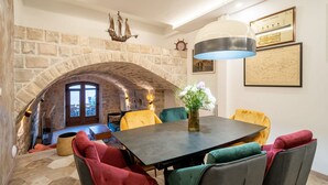 A dining area with a stone arch, a table, chairs, and a hanging light fixture. - Apartment Fortuno (Zupa dubrovacka)