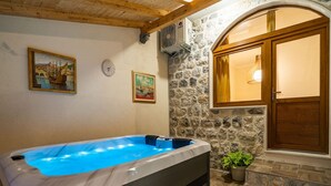 A spa area with a hot tub, stone walls, wooden beams, and artwork on the walls. - Apartment Fortuno (Zupa dubrovacka)