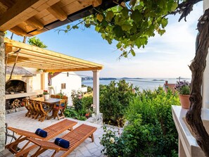 Un patio con un camino in pietra, mobili in legno e vista sul mare.