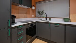 Una cocina moderna con gabinetes grises, horno integrado, pileta y ventana con vista.