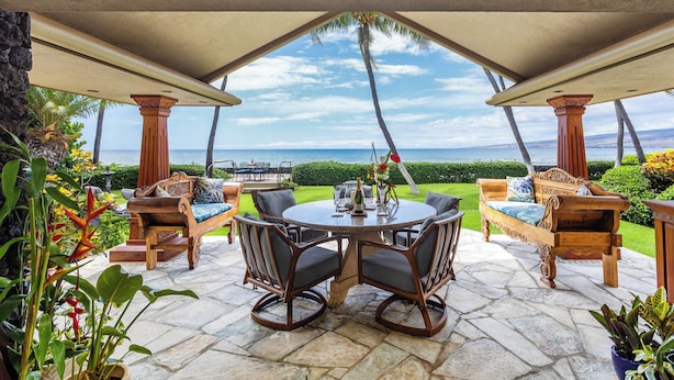 An outdoor patio with a round table, chairs, and a view of the ocean. - Puako Beach Luxury Oceanfront Home- 3 Guest Suites (Waimea)