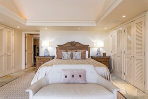 Een slaapkamer met een groot bed, twee nachtkastjes, een bijzettafeltje en een stoel.