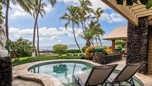 A pool area with lounge chairs, palm trees, and a stone wall. - Puako Beach Luxury Oceanfront Home- 3 Guest Suites (Waimea)