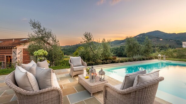 A poolside area with wicker furniture and a view of the mountains. - Valle del Sole Winery Farmhouse (Lucca)