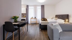 Una habitación de hotel moderna con una cama, un sofá, un escritorio y una mesa de comedor.