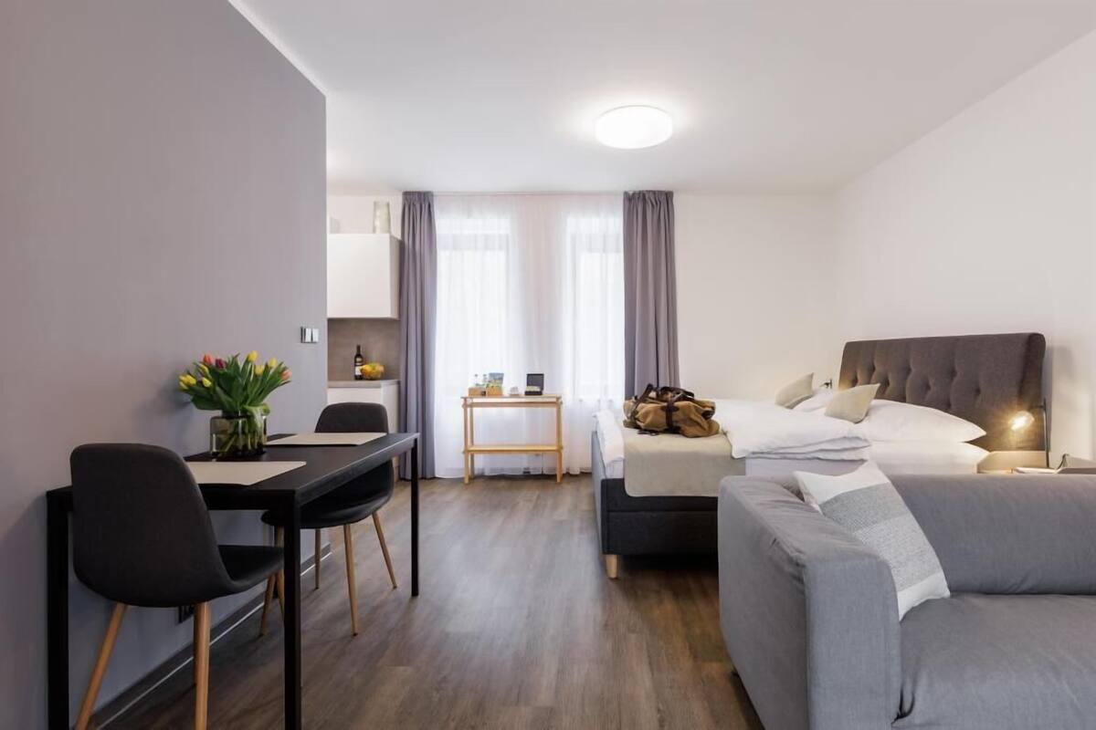 Een moderne hotelkamer met een bed, een slaapbank, een bureau en een eettafel.