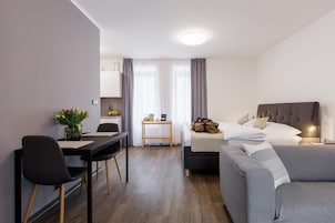 Una habitación de hotel moderna con una cama, un sofá, un escritorio y una mesa de comedor.