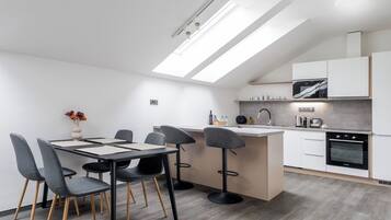A modern kitchen with a skylight, a dining area with a table and chairs, and a built-in oven.