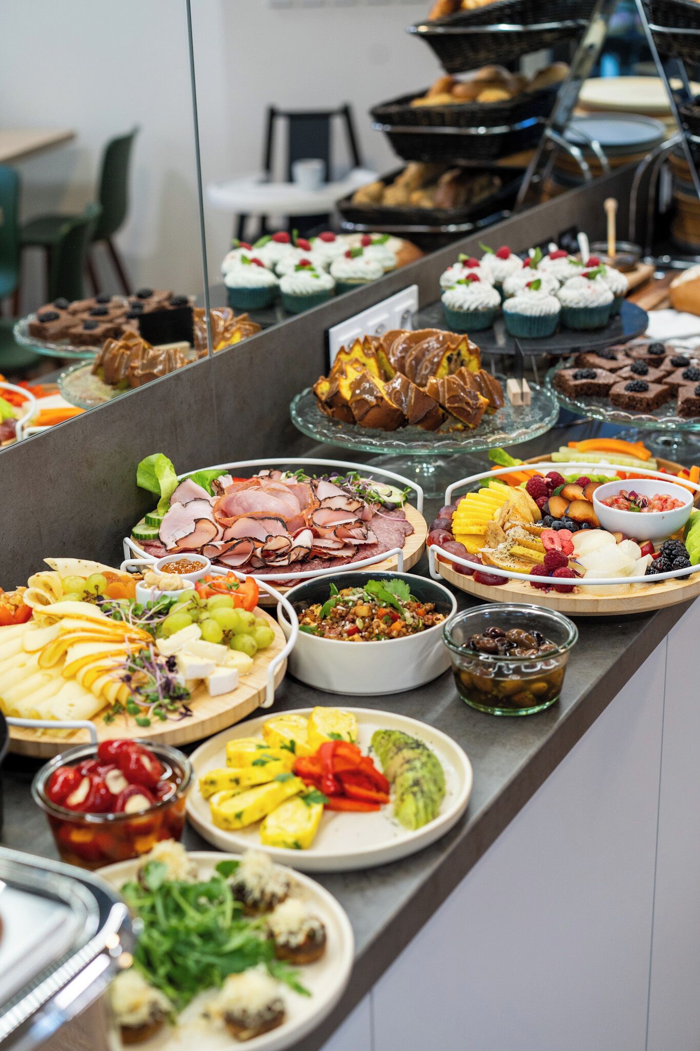 A buffet with various food items including meats, cheeses, fruits, and desserts.
