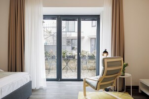 Habitación de hotel con una cama, una silla, una mesita y vistas al exterior.