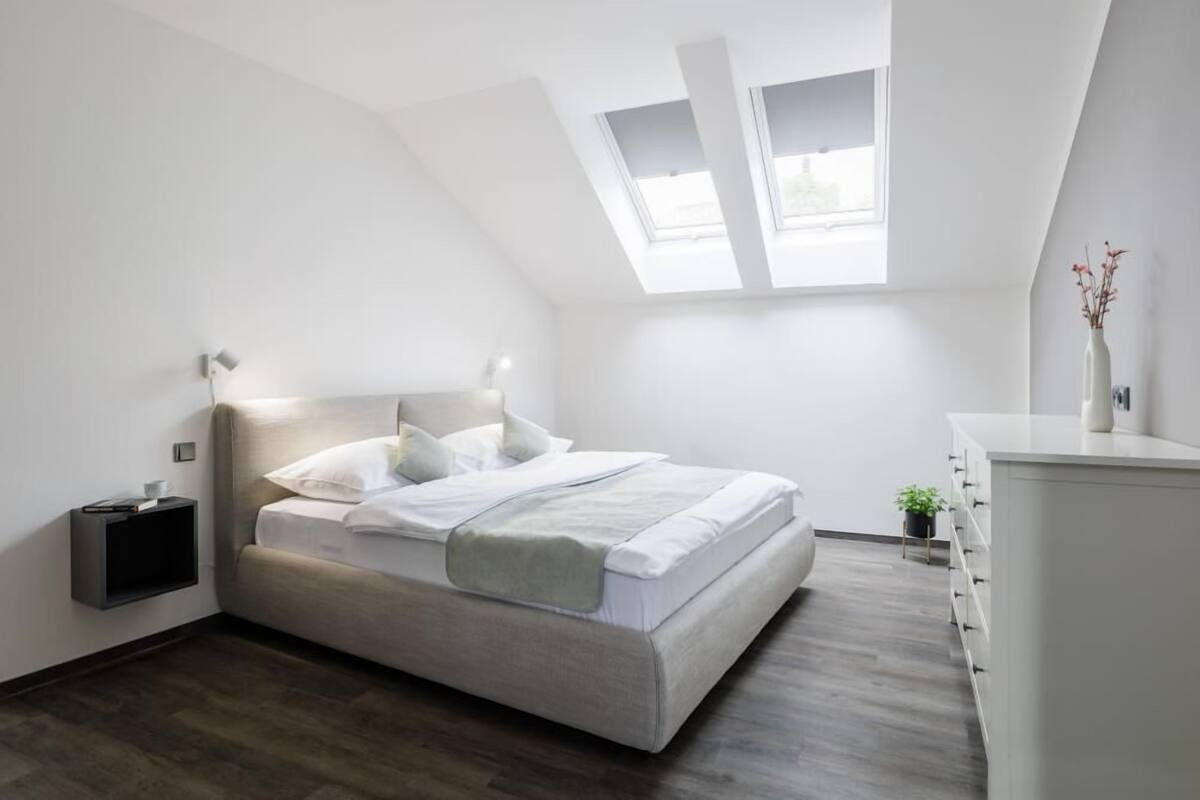 Een moderne slaapkamer met een bed, nachtkastje en een kleine potplant.