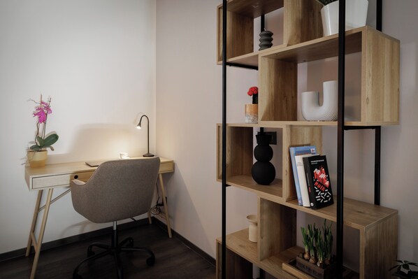Een moderne kantoorruimte met een bureau, stoel en een houten boekenkast met decoratieve objecten.