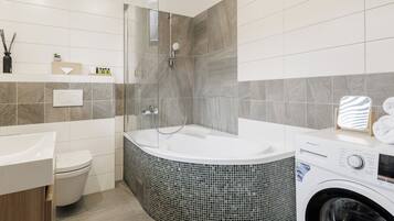 A modern bathroom with a freestanding bathtub, a toilet, and a washing machine.