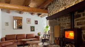 Ein gemütliches Wohnzimmer mit Kamin aus Stein, Ledersofas und einem Fernseher.