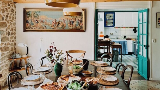 Ein Essbereich mit Tisch, gedecktem Essen, einem Bild an der Wand und Blick in die Küche.