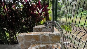A stone sink with a metal faucet, surrounded by a metal fence and lush greenery. - Süßes, Privates Bungalow mit Garden Nahe Manuel Antonio in Einer Ruhigen Gegend (San Martin Quepos)