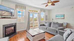 Ein Wohnzimmer mit Kamin, grauen Sofas, einem Couchtisch und einem Deckenventilator.