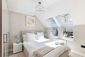 Ein Schlafzimmer mit Bett, Nachttischen, einem Chandelier und Dachfenstern.