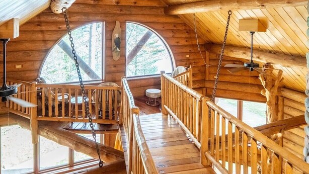 A wooden cabin with a wooden staircase, a small seating area, and large windows. - Redstone, a one-of-a-kind, luxurious 7200 sq. ft. impressive Lakeside log home (Land O' Lakes)