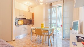 A compact kitchen with modern appliances, a dining area with a table and chairs, and a balcony with a view. - Sirmione Studio Apartment (Sirmione)