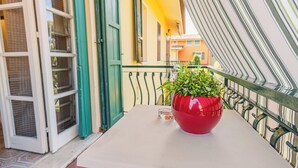 A balcony with a red pot of green plants, a glass of water, and a white table. - Sirmione Studio Apartment (Sirmione)
