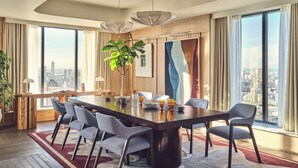 A modern dining area with a large table, chairs, and a city view. - Riverstone Heights (London)