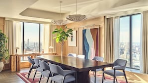 A modern conference room with a large table, chairs, a potted plant, and large windows offering a city view. - Riverstone Heights (London)