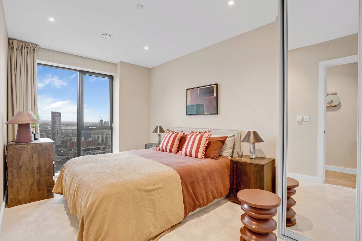 Een moderne slaapkamer met een groot bed, stadszicht en een minimalistisch design.