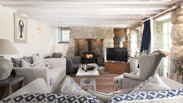 A cozy living room with a stone fireplace, comfortable seating, and a television. - Fairings -  a house that sleeps 8 guests  in 4 bedrooms (St Ives)