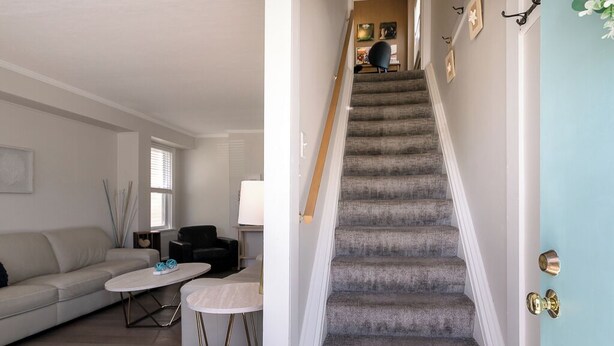 Un escalier menant à un deuxième étage, un salon avec un canapé et une table basse, et une porte dotée d’une poignée en laiton.