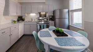 Une cuisine moderne avec des meubles blancs, un réfrigérateur en acier inoxydable et une table à manger agrémentée de sets de table bleus.